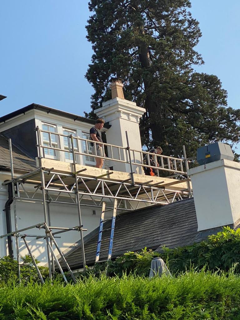 DDJ scaffolders on a guarded working platform at roof level beside a chimney stack