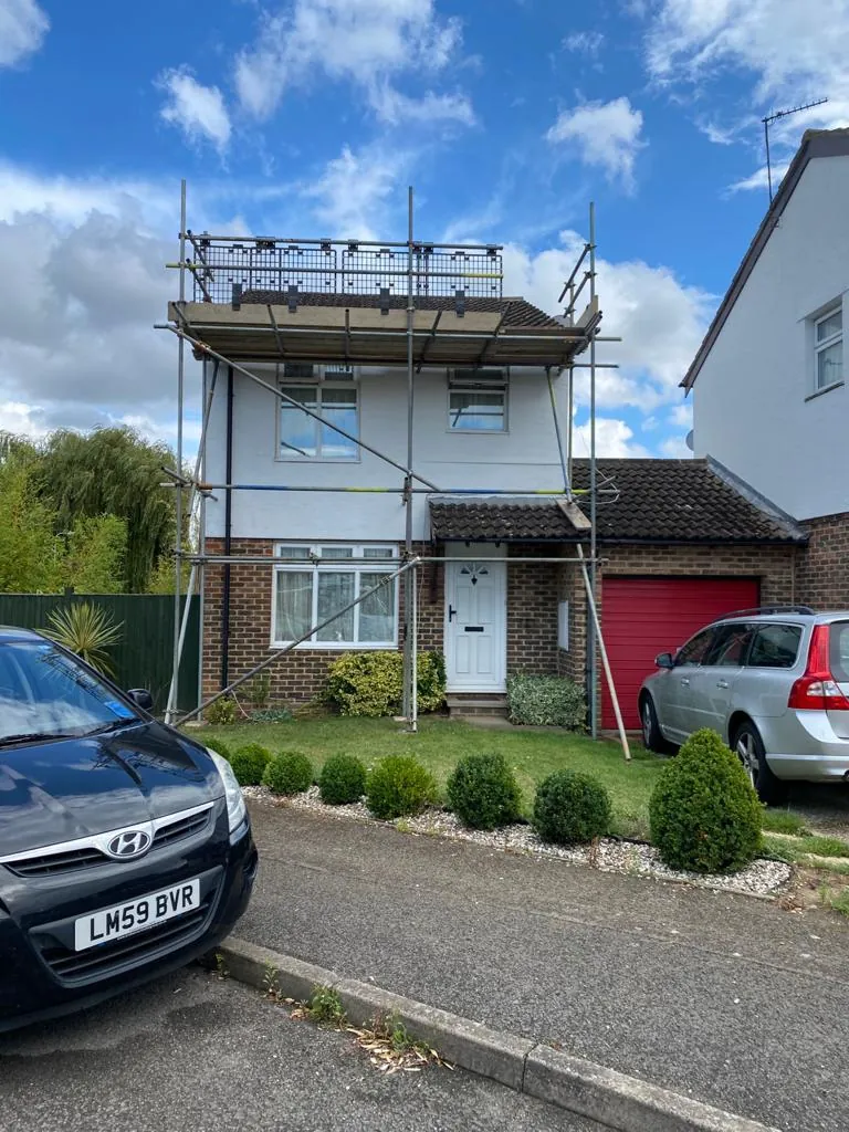 A single lift of scaffolding across the front of a house, boarded and guarded at roof level