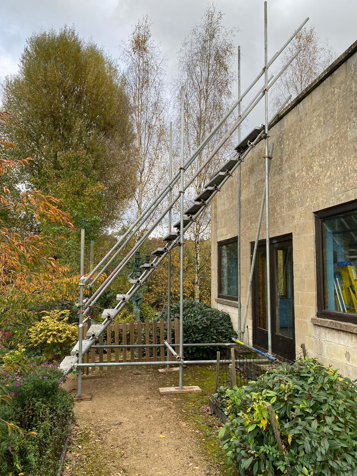 A scaffold staircase run with treads and handrails climbing between boarded lifts