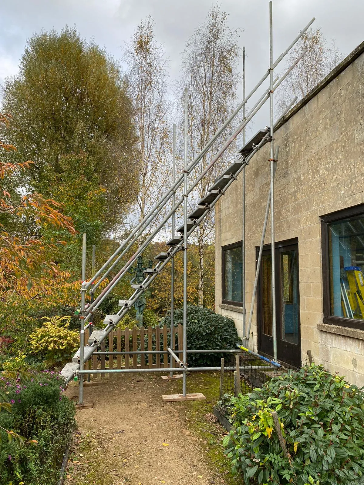 A scaffold staircase run with treads and handrails climbing between boarded lifts