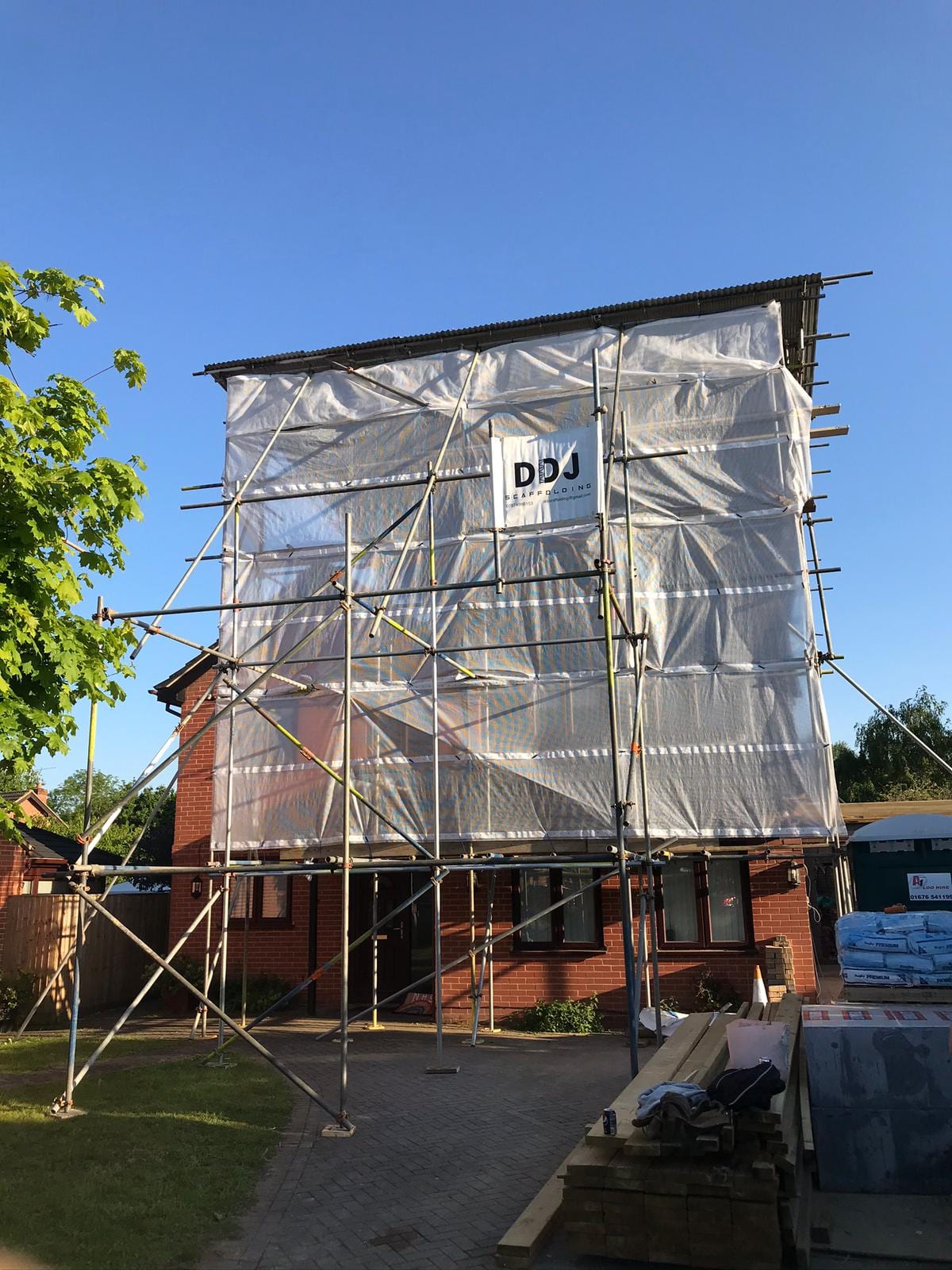 A pitched temporary roof sheeted over a building, supported on the scaffold around it